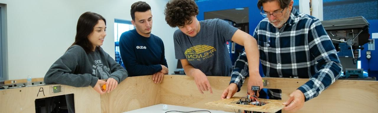 Students working on a robot with faculty